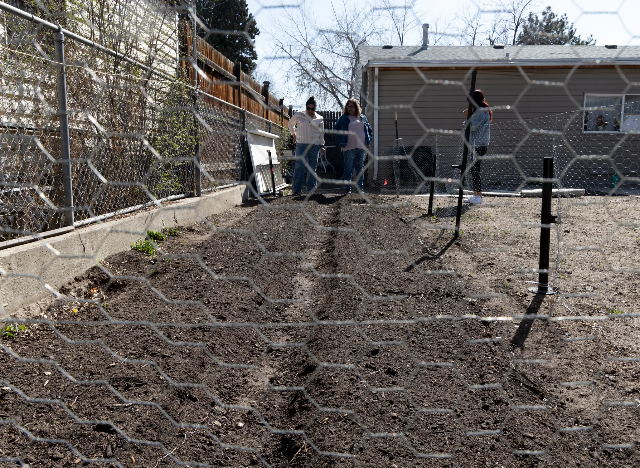 Manquera and other Re:Vision staff examine a backyard garden which is in the early stage of the growing season. Photo: Carly Rose, Rocky Mountain PBS