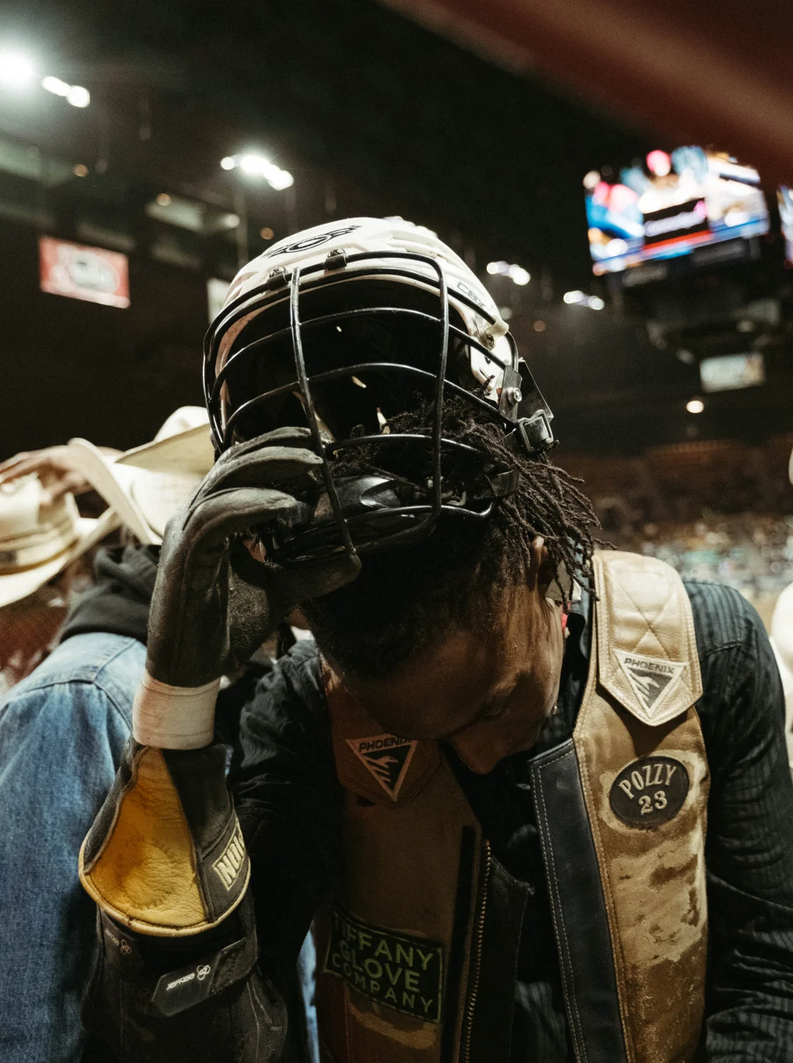 A cowboy removes his headgear after bull riding. 