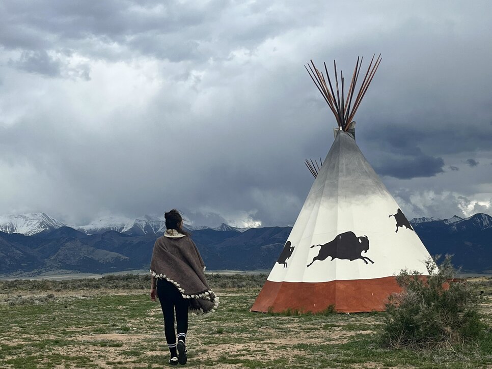Tipi in Moffat with Fernanda walking and storm clouds