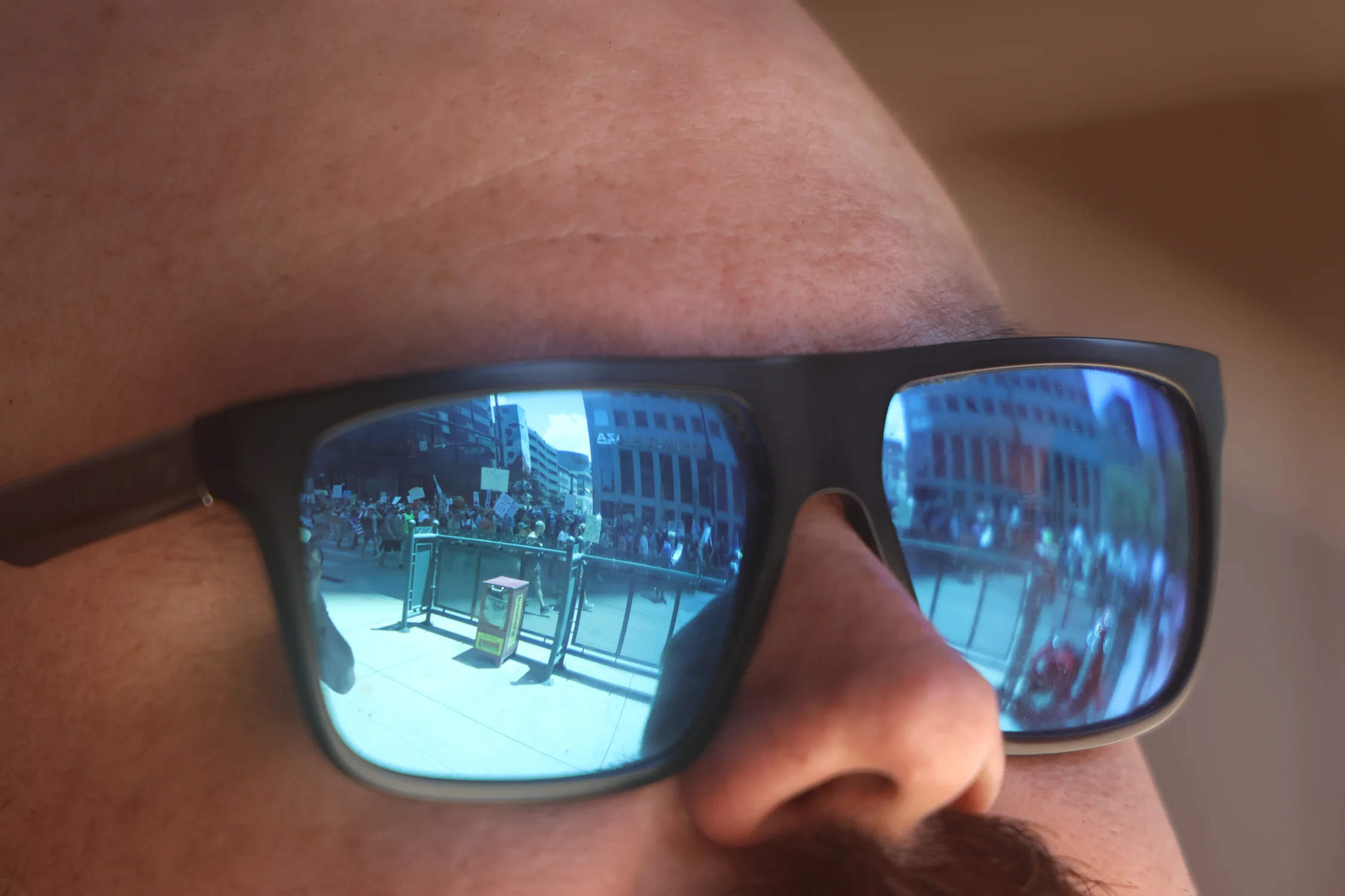 A view of the march as seen from a security guard's glasses outside the Brown Palace Hotel in Denver. Photo: Kyle Cooke, Rocky Mountain PBS