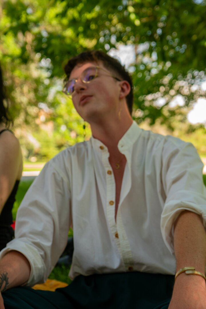 Jo Carroll leans back with friends under the shade of a tree in summer time