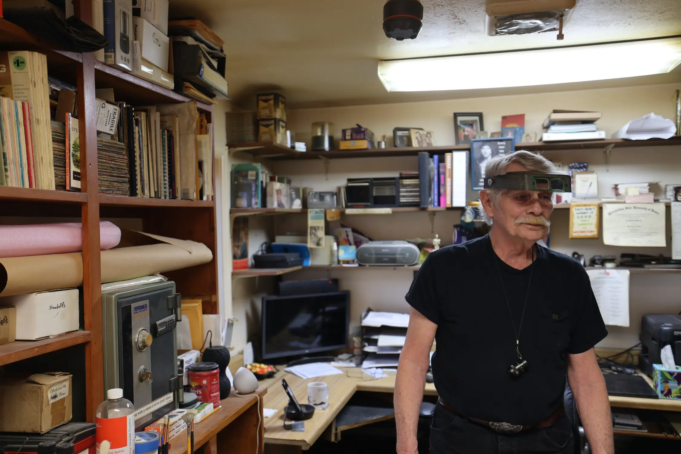 Jim Stevens in his home studio, complete with his magnifying glasses and minifying lens. These tools are crucial for Jim's process as they help fill  gaps in his vision. Photo: Sarah Shoen, Rocky Mountain PBS