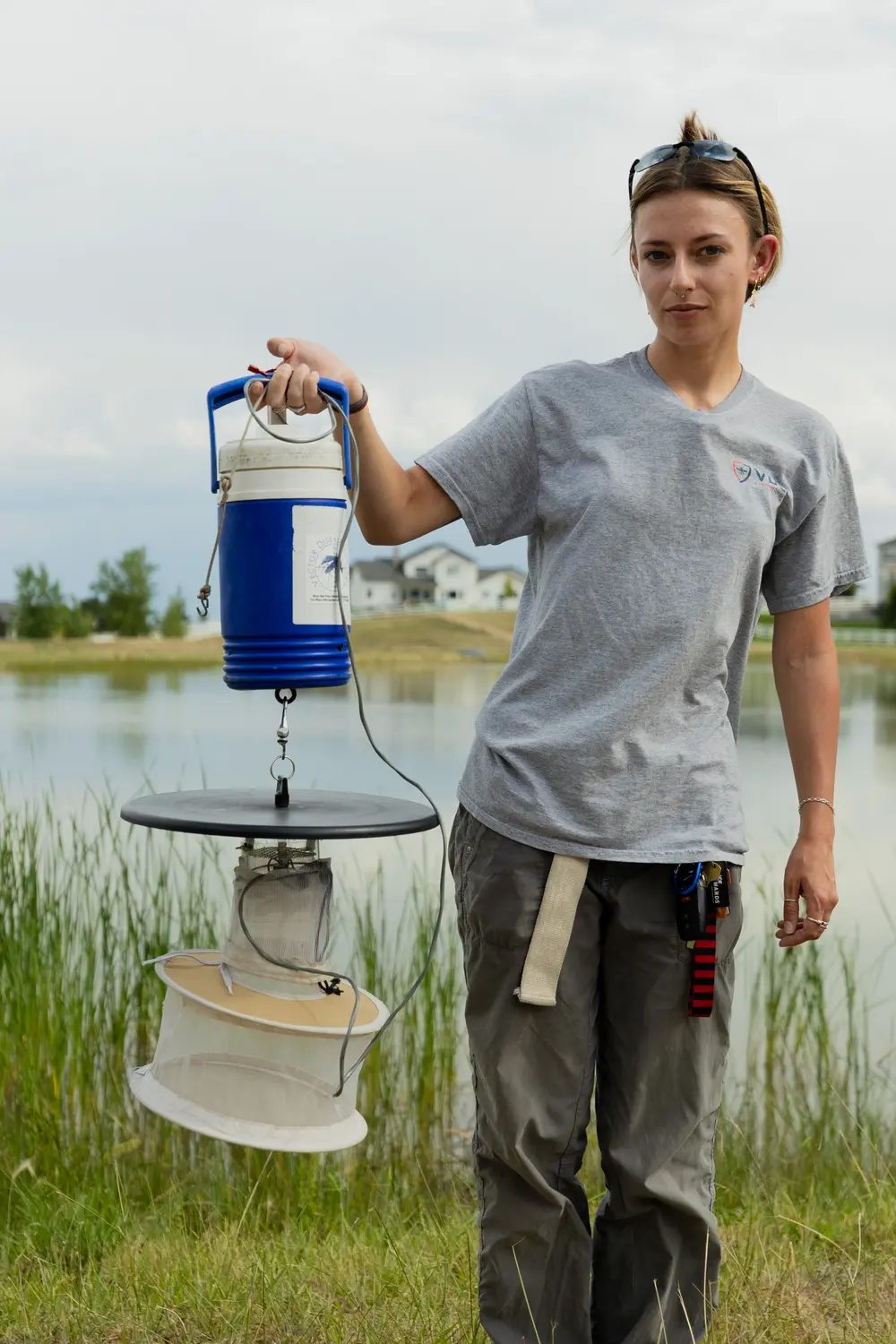 Ellie McEwen poses with a CDC light trap used to trap adult mosquitos at a site near Severance, Colorado. Photo: Cormac McCrimmon, Rocky Mountain PBS