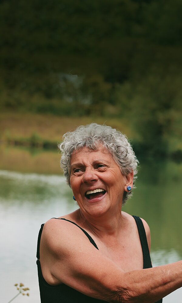 Happy, healthy older woman is smiling and laughing whilst paddle boarding