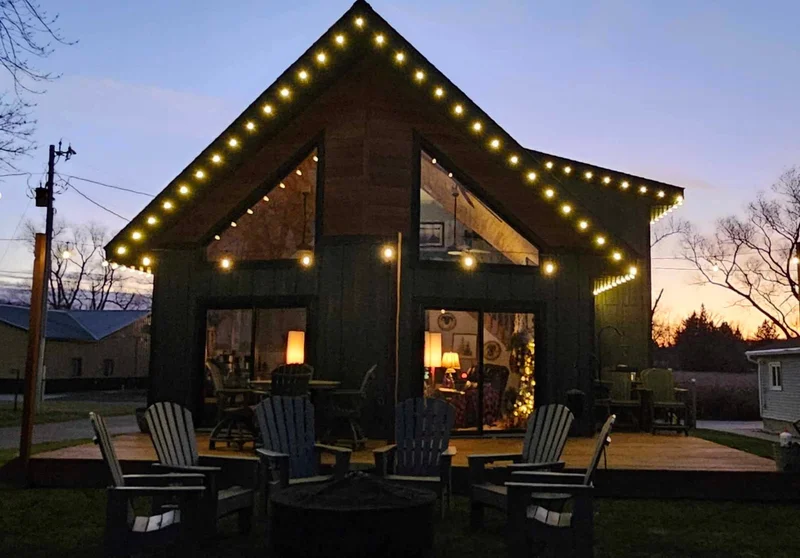 Lake-area house with warm white lights along peaks and dormers