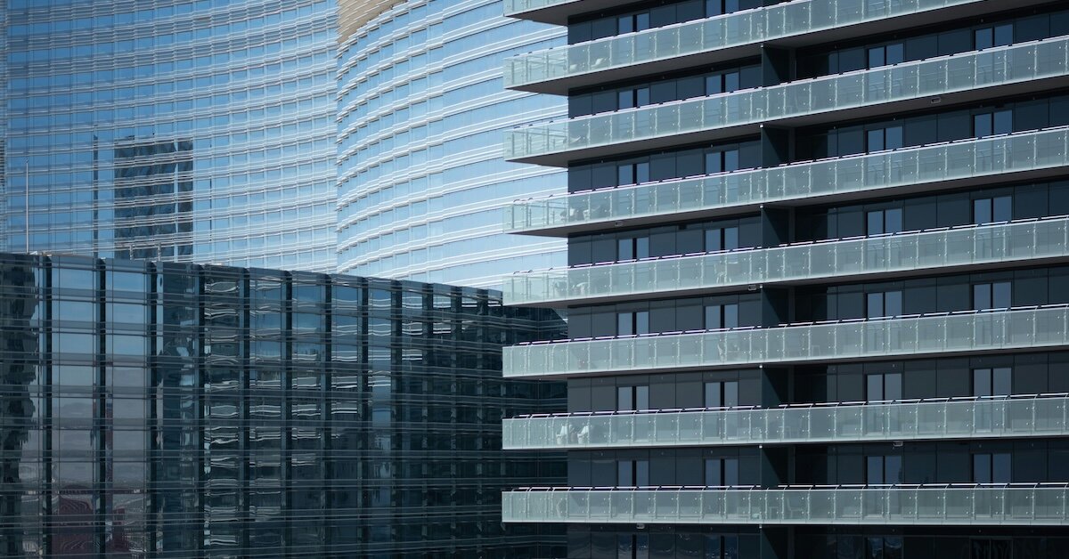 A tall set of hotel buildings lined next to eachother with glass balconies