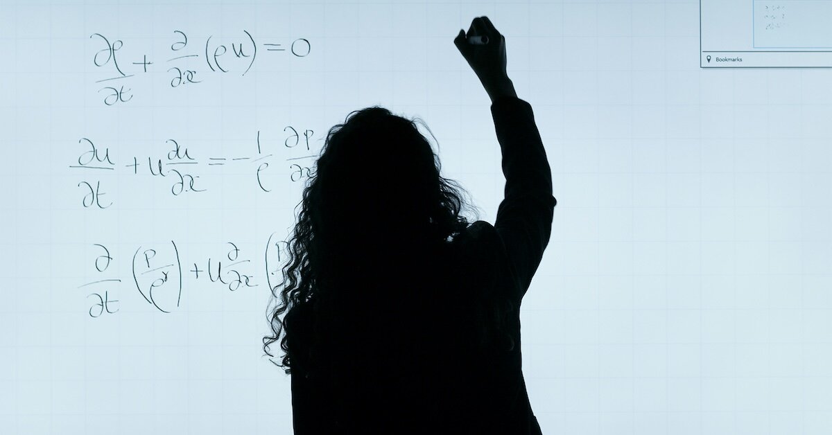 A woman calculating equations like risk on a whiteboard