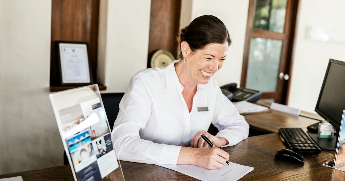A woman sits at a desk filling out paperwork