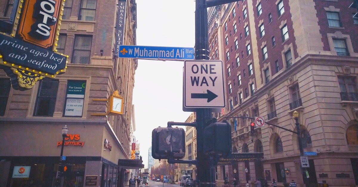 a one way street sign in downtown Louisville, surrounded by multifamily apartment buildings