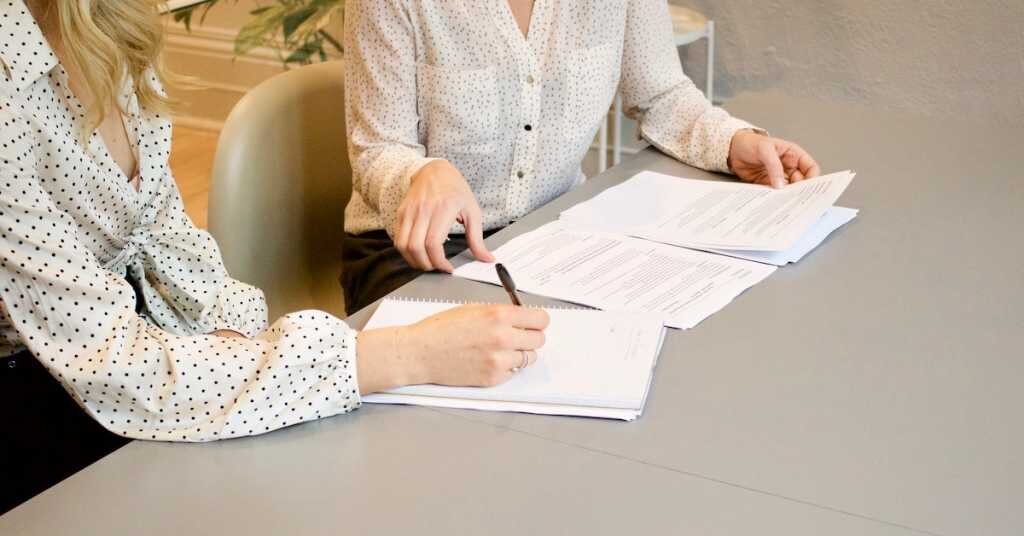Two ladies discuss business over signing papers