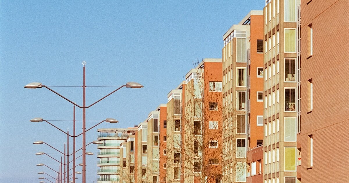 A row of buildings are lined with power lines, colored orange and yellow.