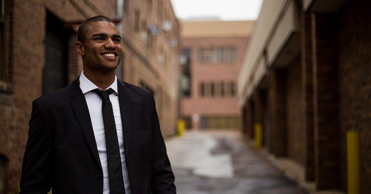A young professional is smiling, looking up at a building