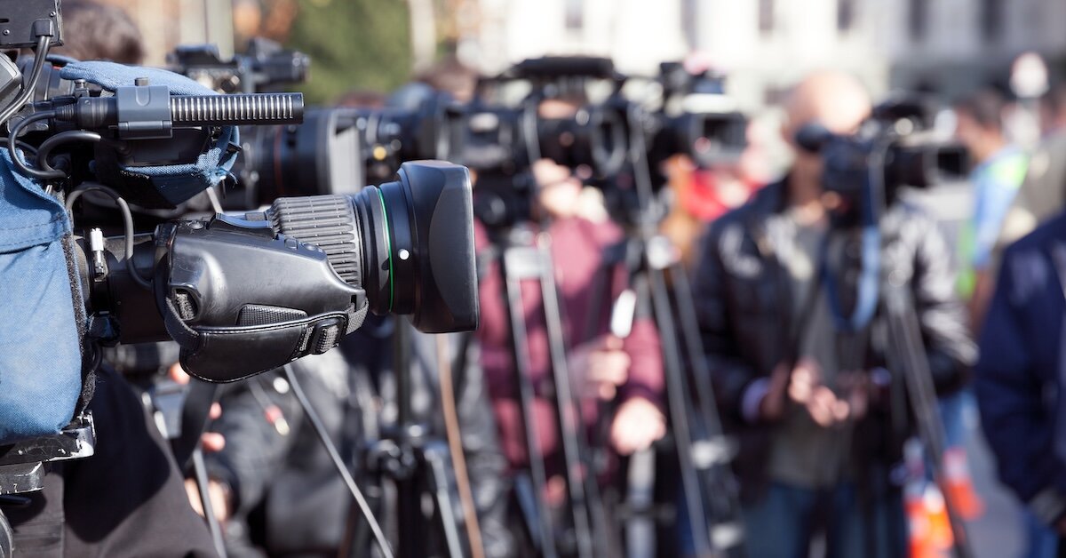 A row of journalist cameras stand pointing towards the right side of the image