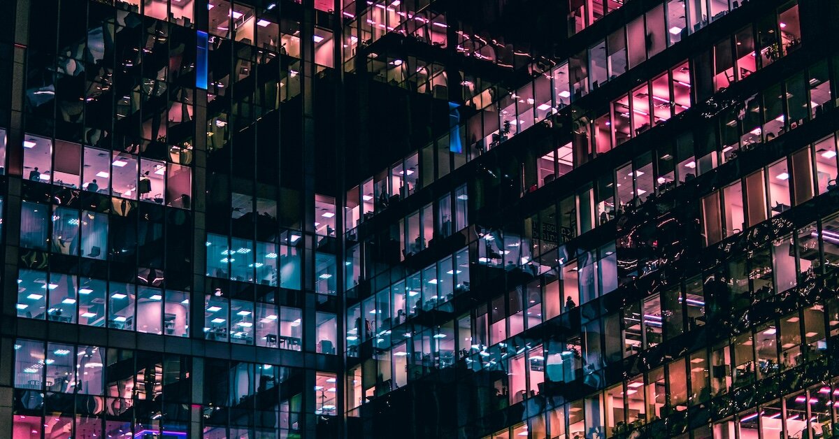Many office buildings with different color lights emerging through the windows