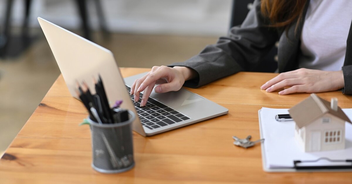 A broker works at a laptop sitting at a desk
