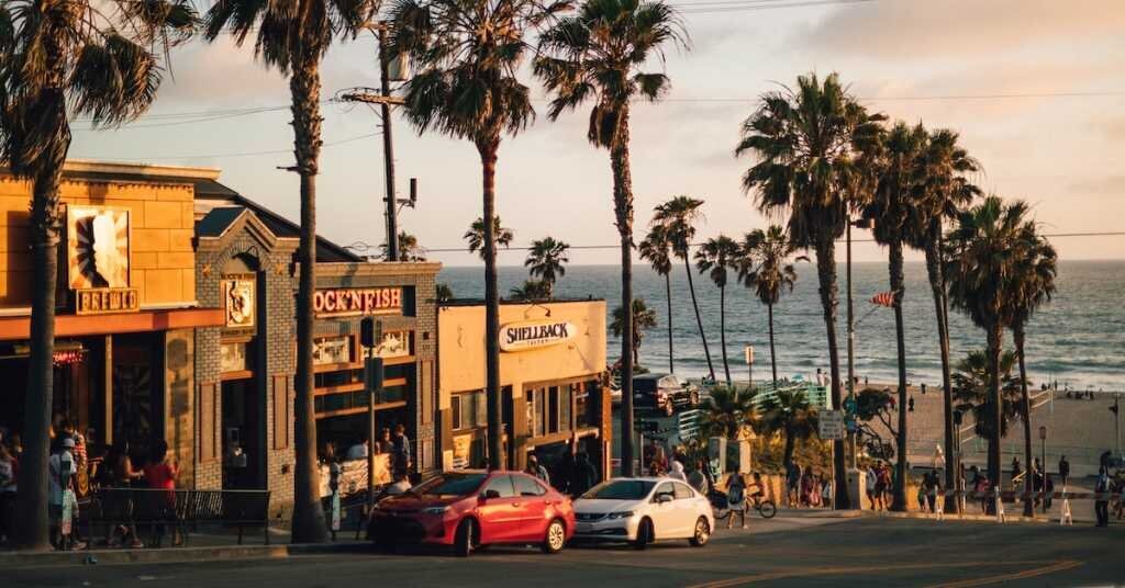 Retail shops line an avenue with a clear path to the beaches of Los Angeles