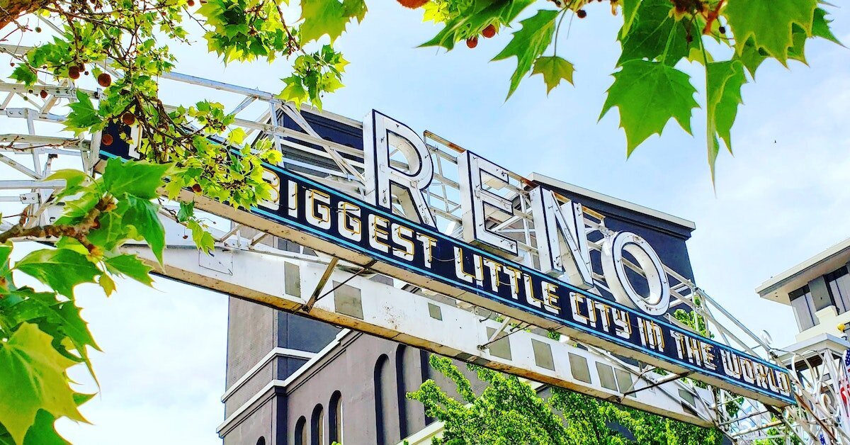 A daytime view of the Reno welcome sign surrounded by greenery
