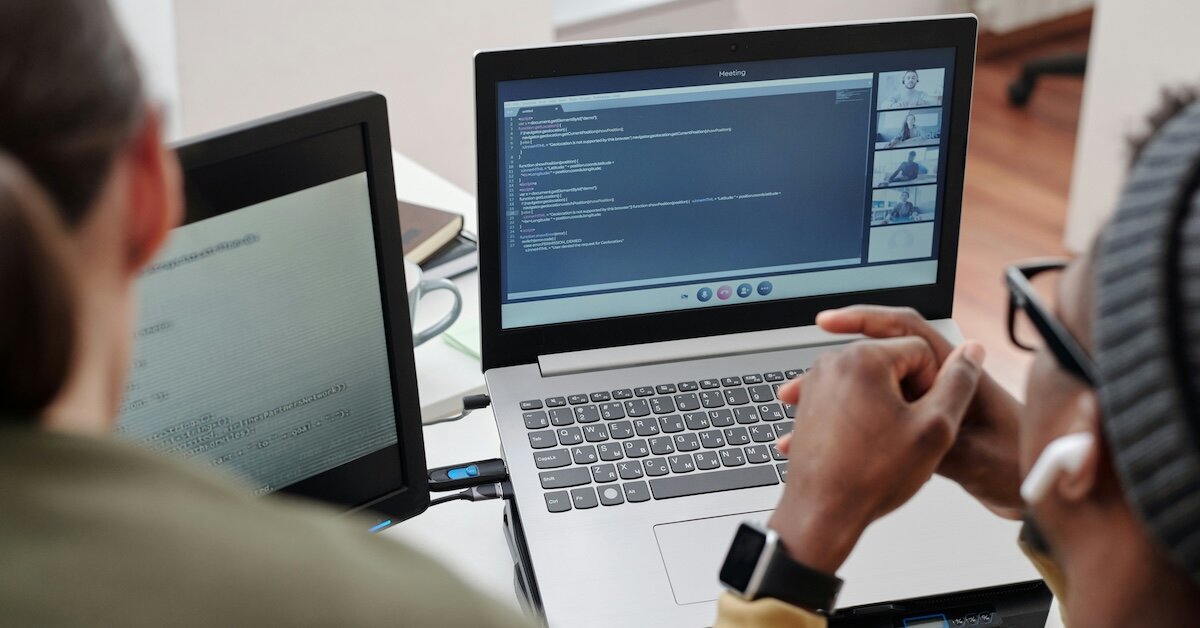 Two people are sitting on a conference call reviewing code for a software program