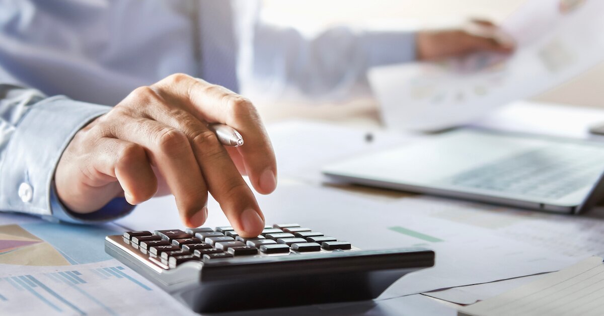 a gentleman calculating numbers while looking at data and a computer screen