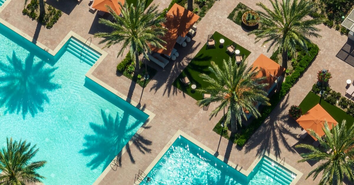 A resort grounds with pools and cabanas framed by palm trees