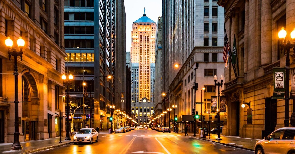 A busy Chicago street downtown with a distinct skyscraper framed by two large buildings