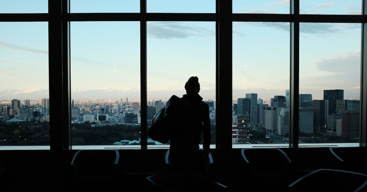 A business person looks out at a city from a skyrise office window
