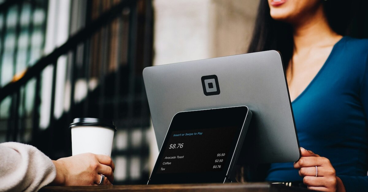 a woman helps a coffee shop customer check out