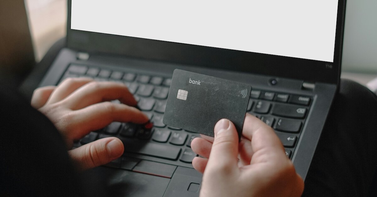 a person holding a credit card is inputing their information into a laptop computer