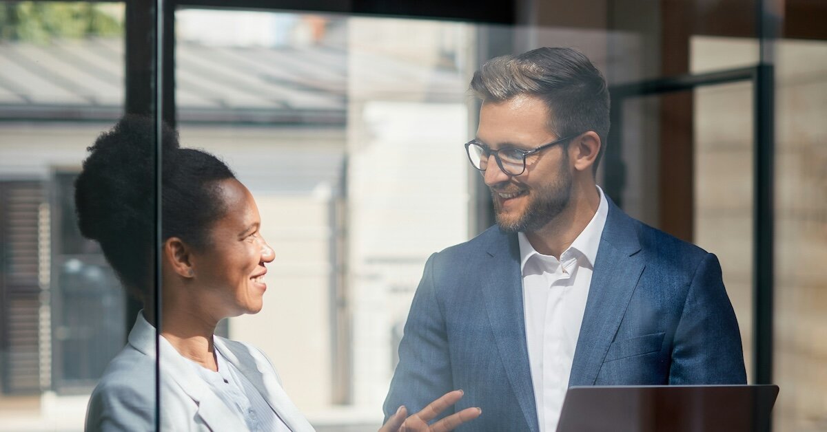 Two business professionals in conversation with a laptop in the foreground