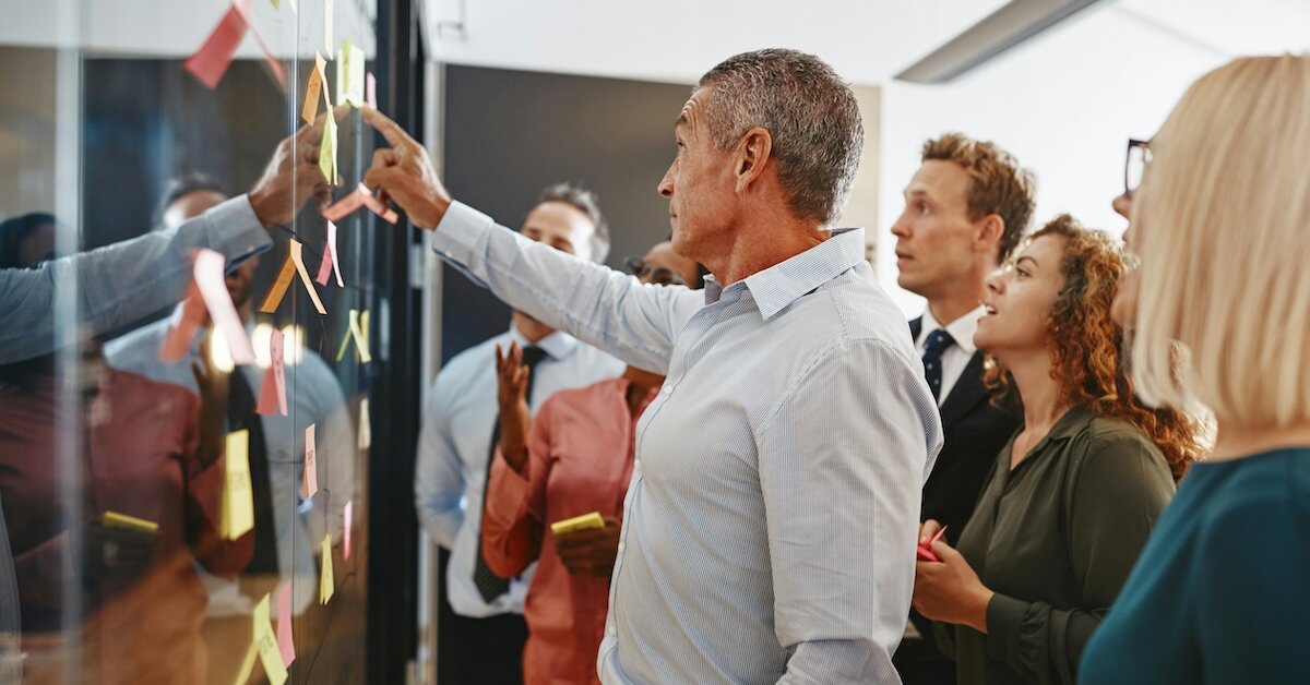 A business team looking at displayed post-it notes on the conference room wall