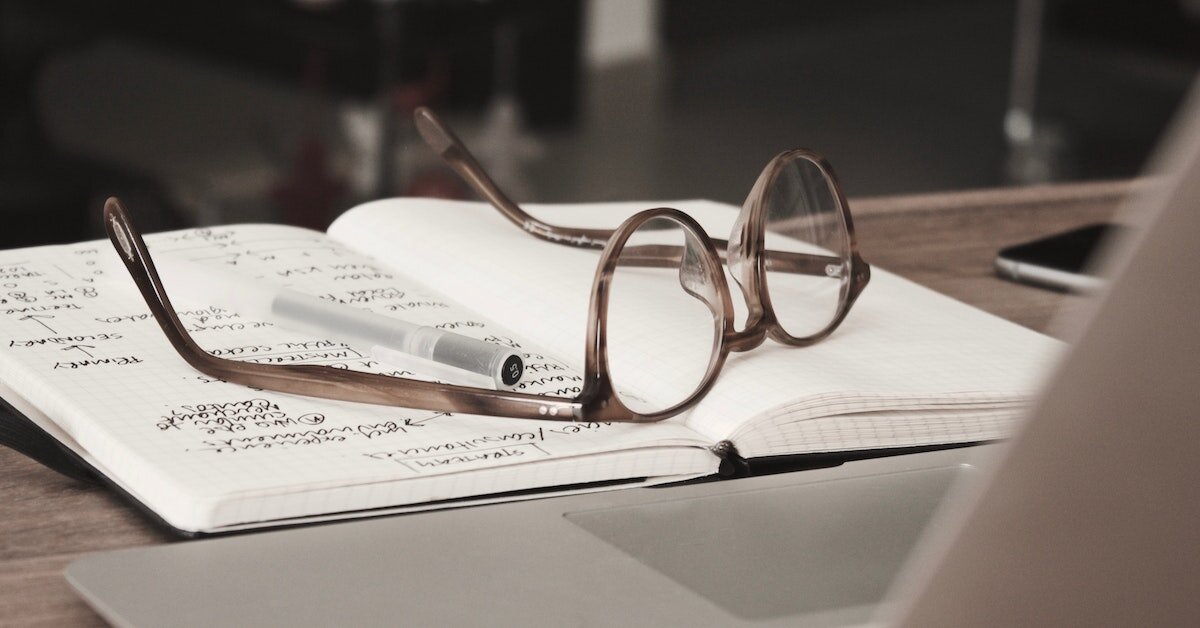 A pair of glasses atop a research notebook.