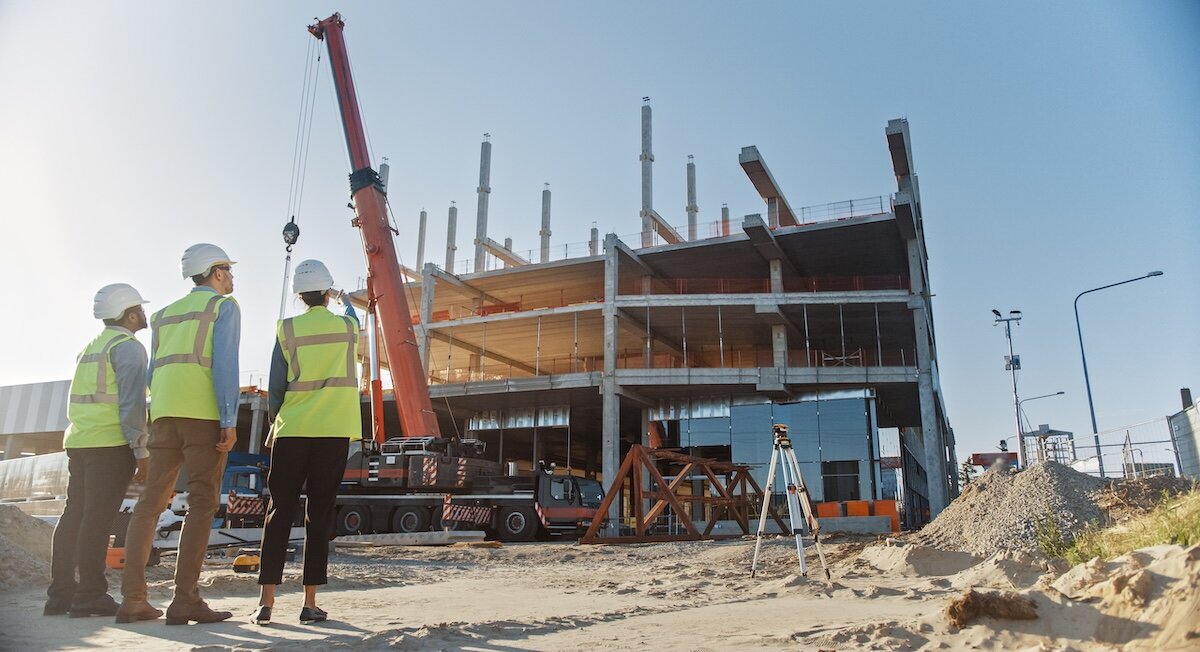 construction workers survey a development surrounded by dirt and equipment