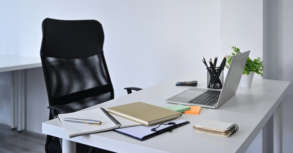 empty desk chair with papers, notebooks and a laptop