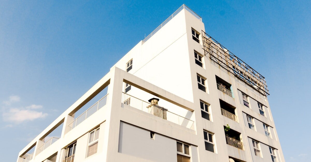 The outside of a white apartment building with rooftop amenities