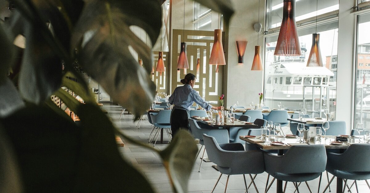 A server sets a table in a well-lit restaurant