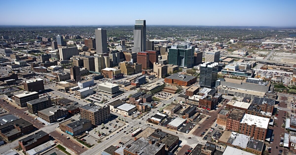 A high-contrast aerial drone view of Omaha's downtown buildings and retail property in the foreground