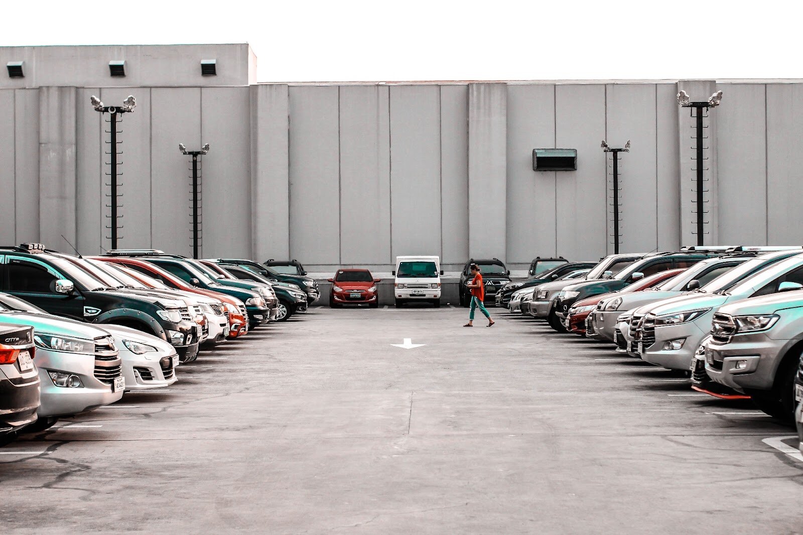 A woman walks to her car in a commercial parking lot