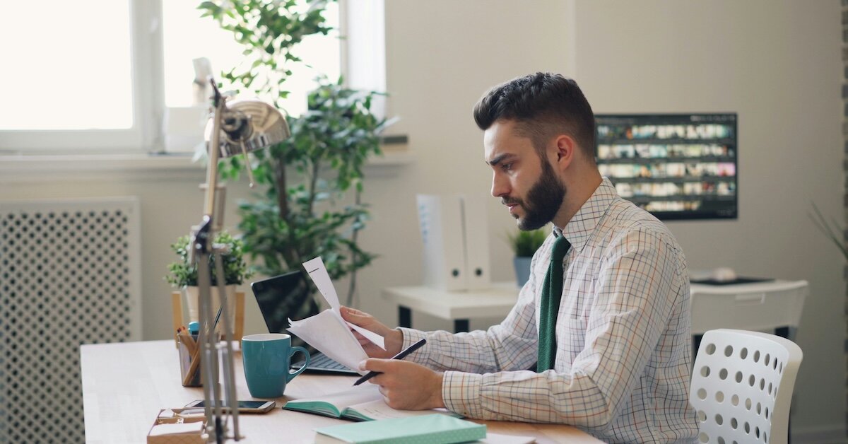 A man reviewing a set of contracts such as a reciprocal easement agreement sitting at a desk