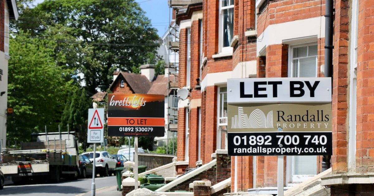 A street with for-rent signs posted outside the buildings