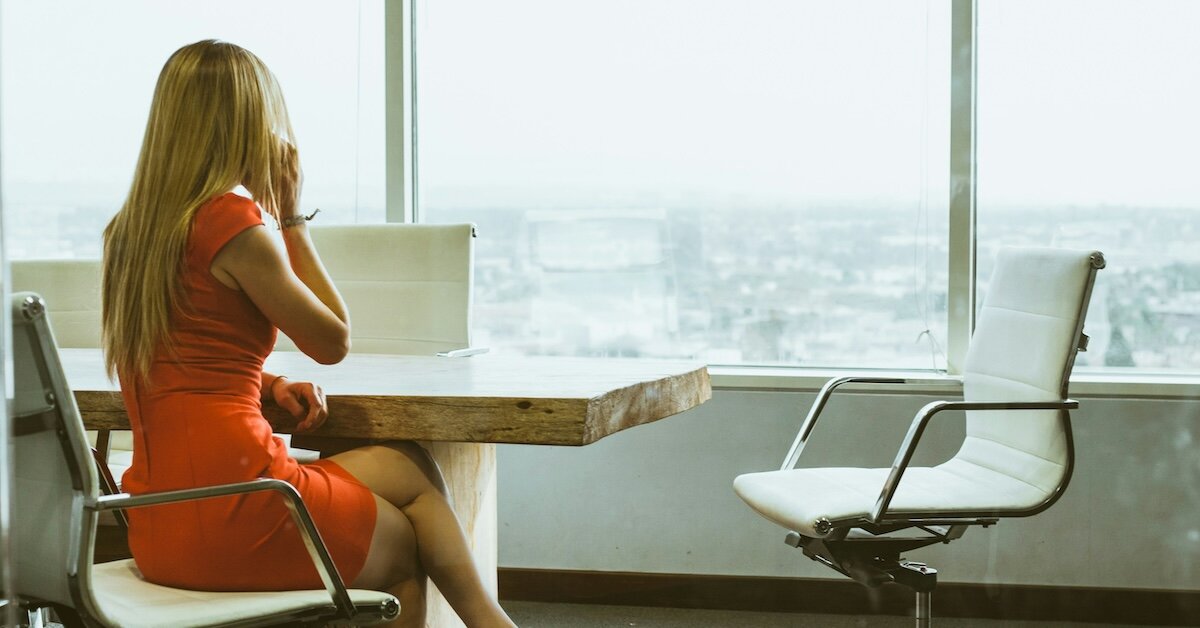 A woman is on the phone sitting in a conference room in a high-rise office building.