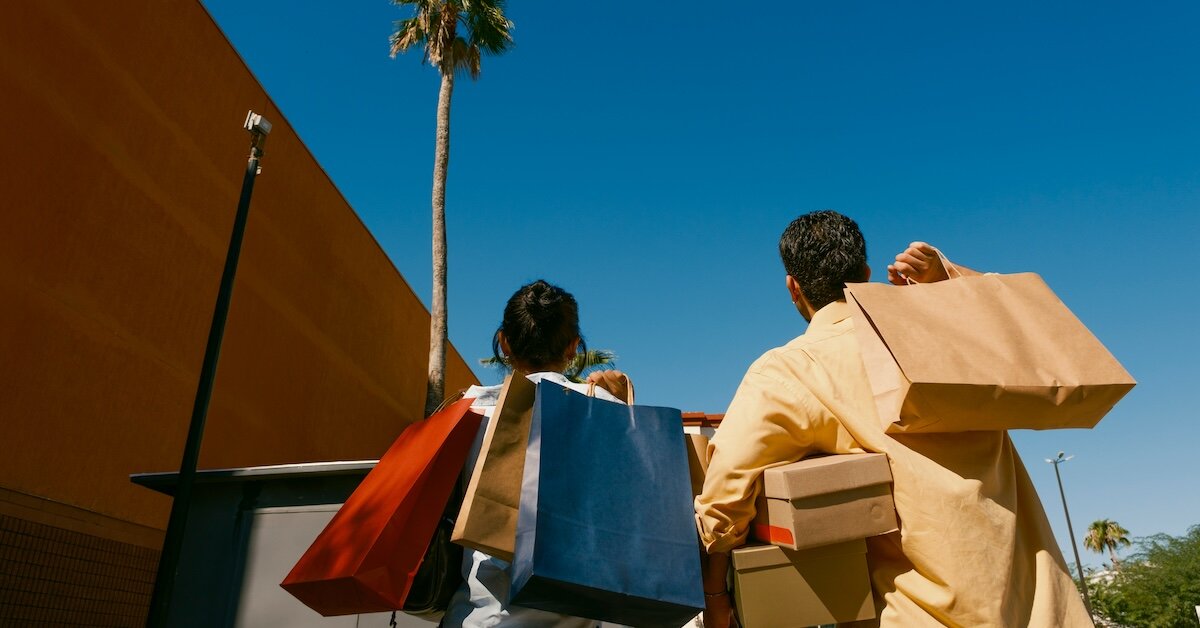 two shoppers looking up at a retail store holding bags