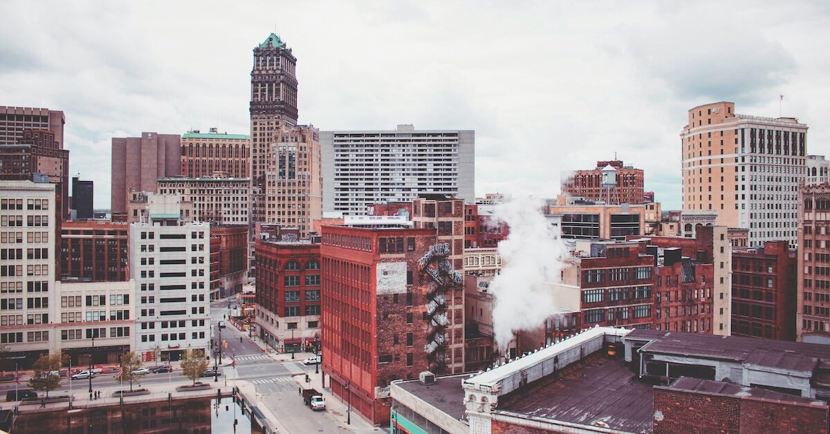A downtown corner of Detroit with steam emerging from a factory
