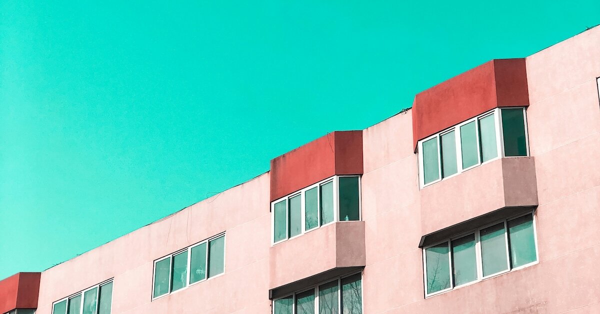A pink apartment building against a teal-blue sky
