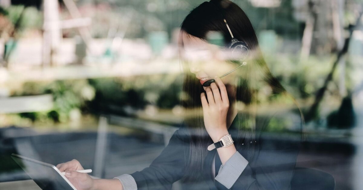 A woman broker is on a headset cold calling a potential CRE prospect