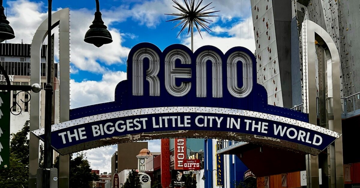 A sign over a street that says "Reno, the biggest little city in the world"