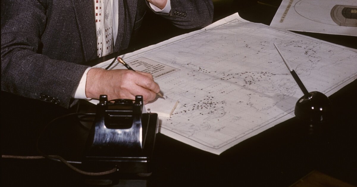 A person looks over a map with sites selected on their desk