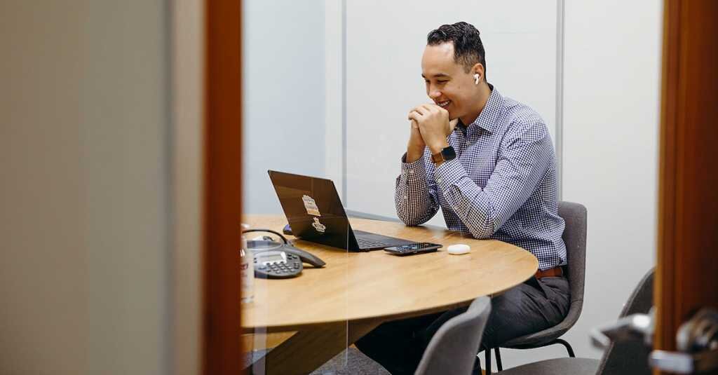 a crexi employee sits smiling at the computer in a conference room meeting