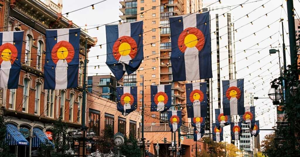 Colorado's state flag hangs in rows between tall buildings in Denver