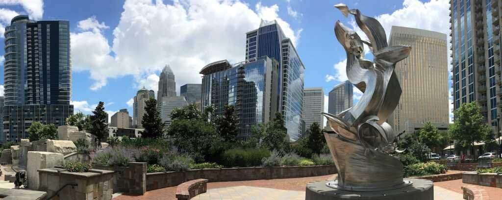 A sculpture in stands against the city skyline in downtown Charlotte