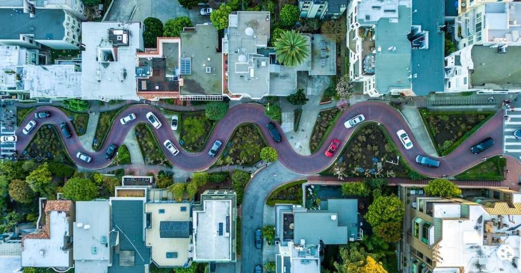 A neighborhood street with cars winding down a San Francisco hill as seen from an overhead drone